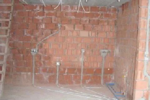 Ruwbouwbekabeling van een residentiële installatie tegen baksteen