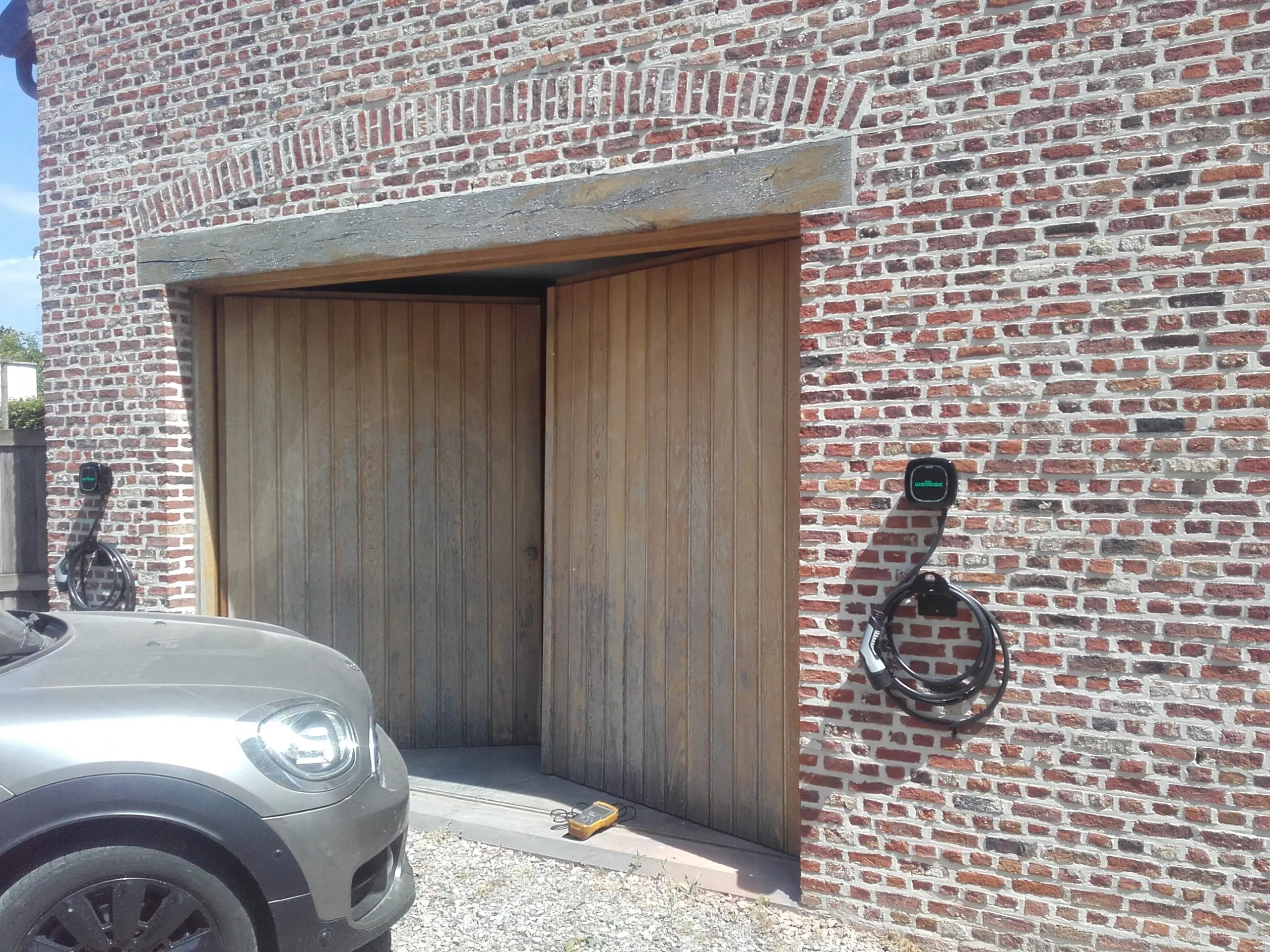 Wallbox-laadpaal aan een woning met een elektrische wagen ervoor